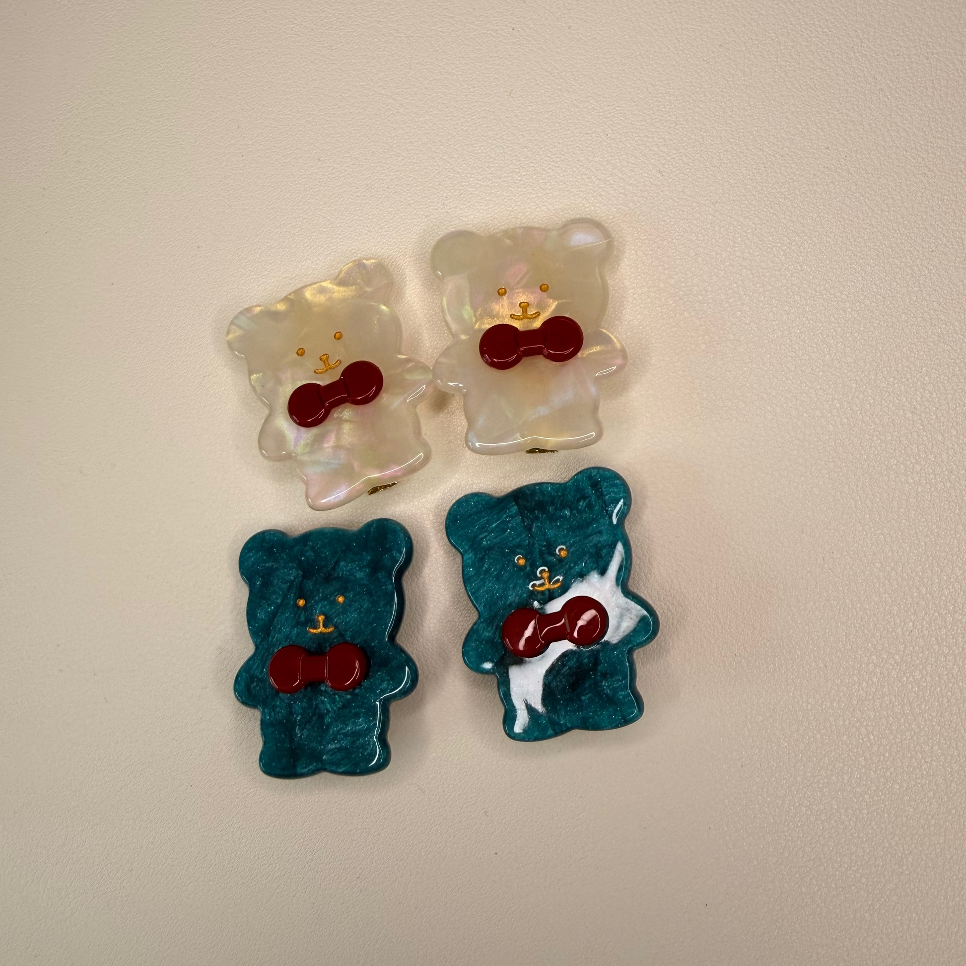 Four colorful bear-shaped candies with red bow ties on a beige background