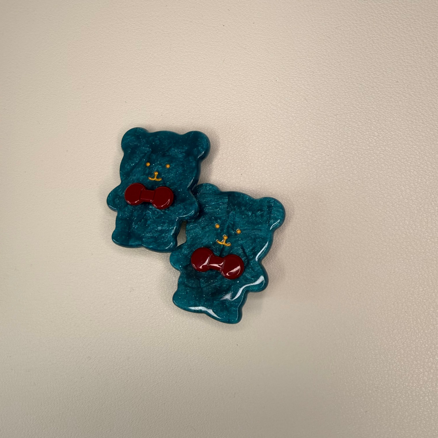 Two blue jelly bear candies with red hearts on a beige background