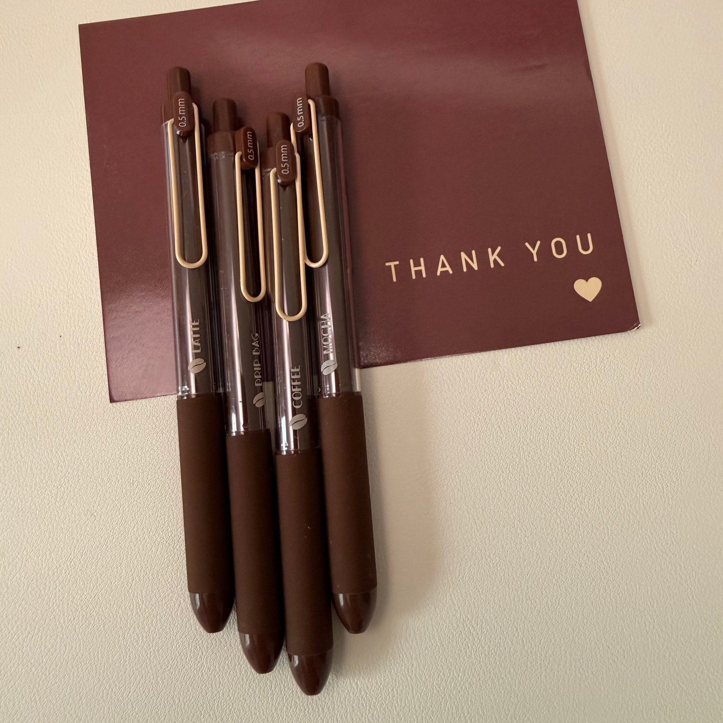 Set of pens with a 'Thank You' card on a beige background